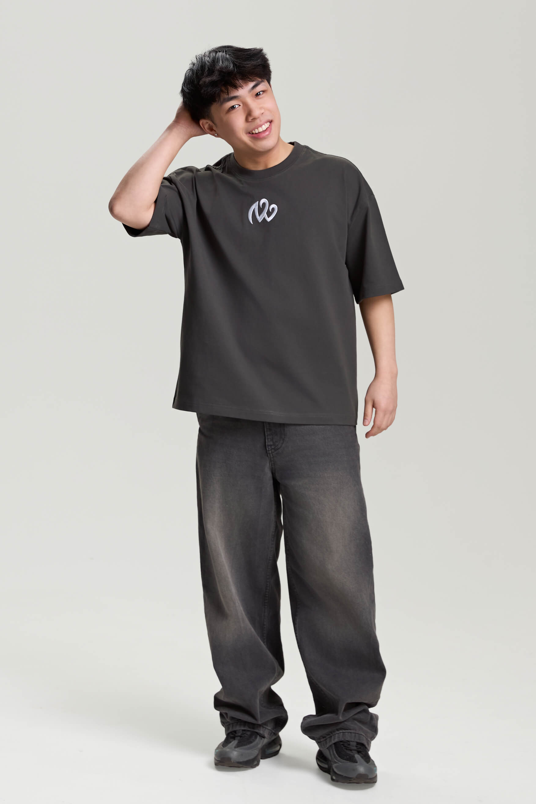 Model wearing gray loose tee with white logo print