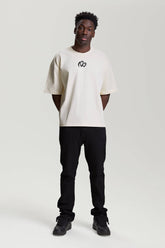 Model wearing beige NV Loose T-Shirt with black logo by TURN ENVY TO LOVE