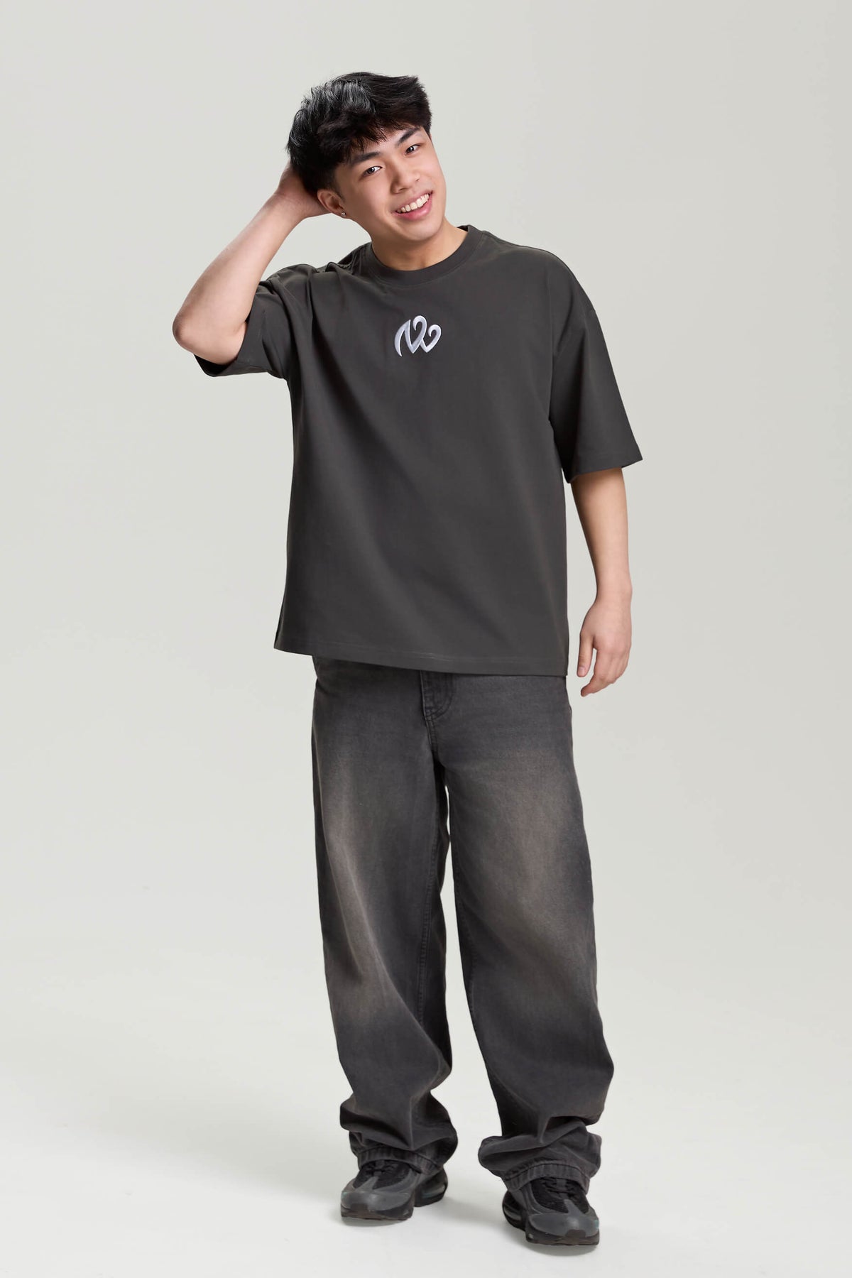 Model wearing gray NV Loose T-Shirt with white logo print – oversized streetwear look by TURN ENVY TO LOVE